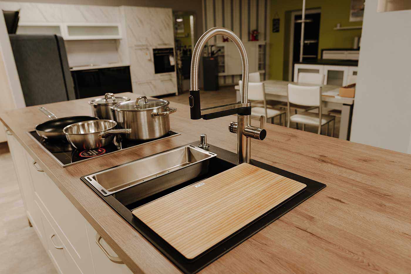 Detailfoto Spüle einer weißen Landhausküche mit Kücheninsel und Holzarbeitsplatte