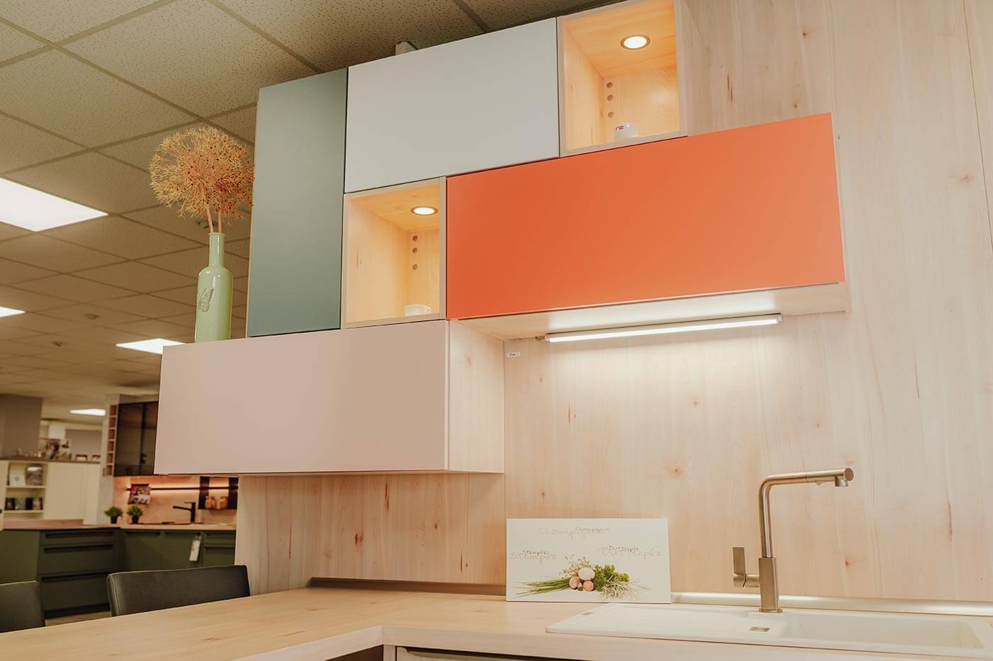 Küche aus Holz mit Fronten in orange & mintgrün in der Küchenausstellung Matthäs